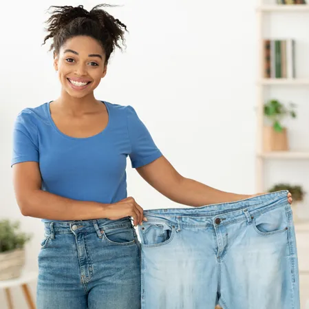 A woman holding a pair of old pants up.