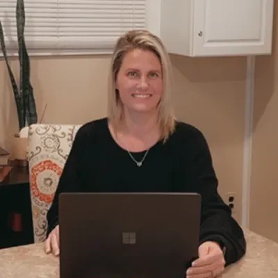 Wellness Care Baltimore MD Jamie Meet The Team Jamie smiling while sitting behind a computer.
